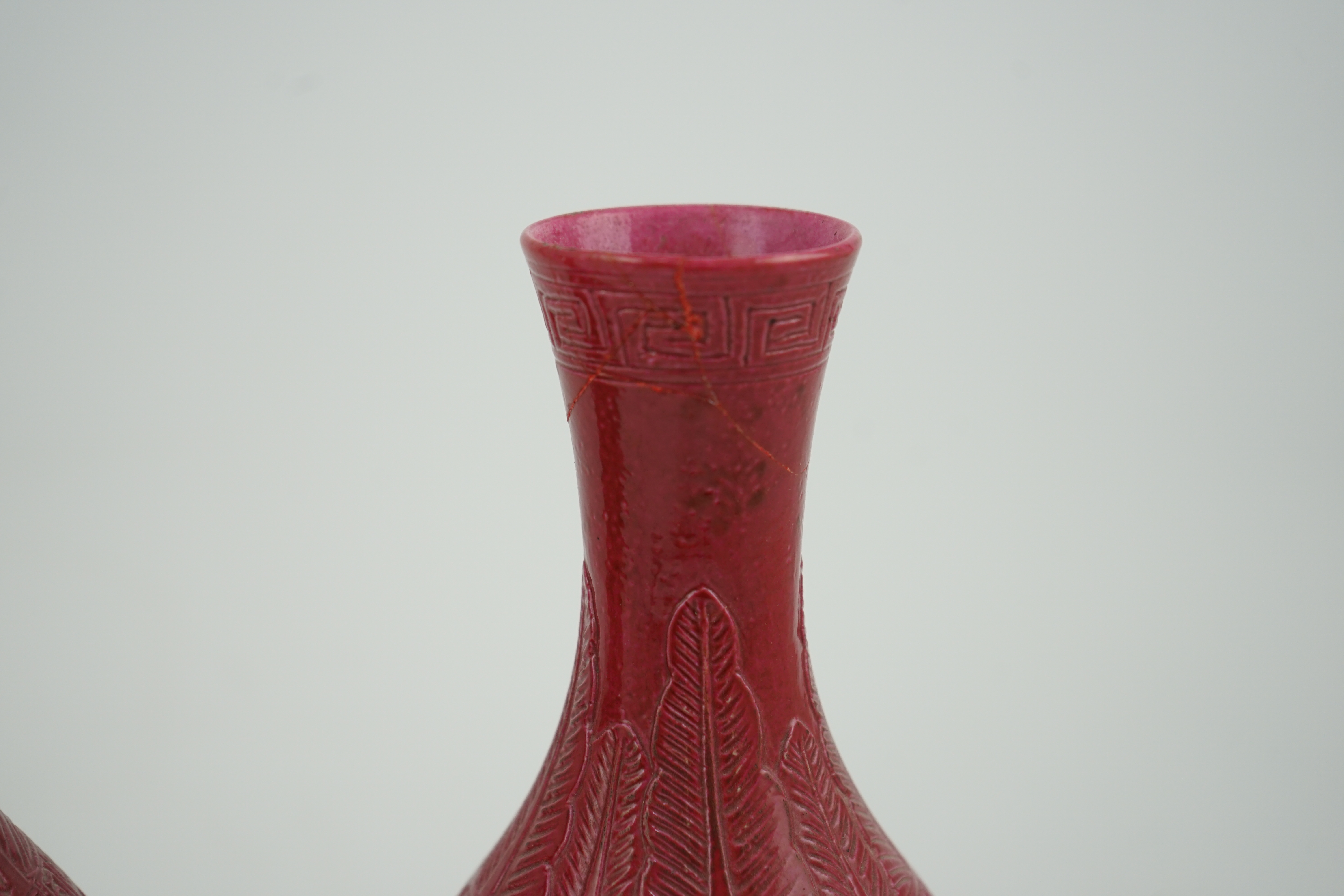 A pair of Chinese ruby ground ‘lotus’ bottle vases, late 19th century, each carved in relief with lotus flowers, scrolling tendrils and leaves, both with carved stands, 24cm high. Condition - one vase the neck broken bot